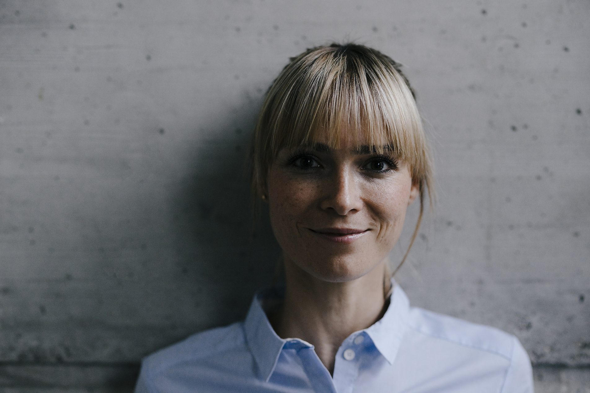 Leonie an der Betonwand, Hände in den Taschen